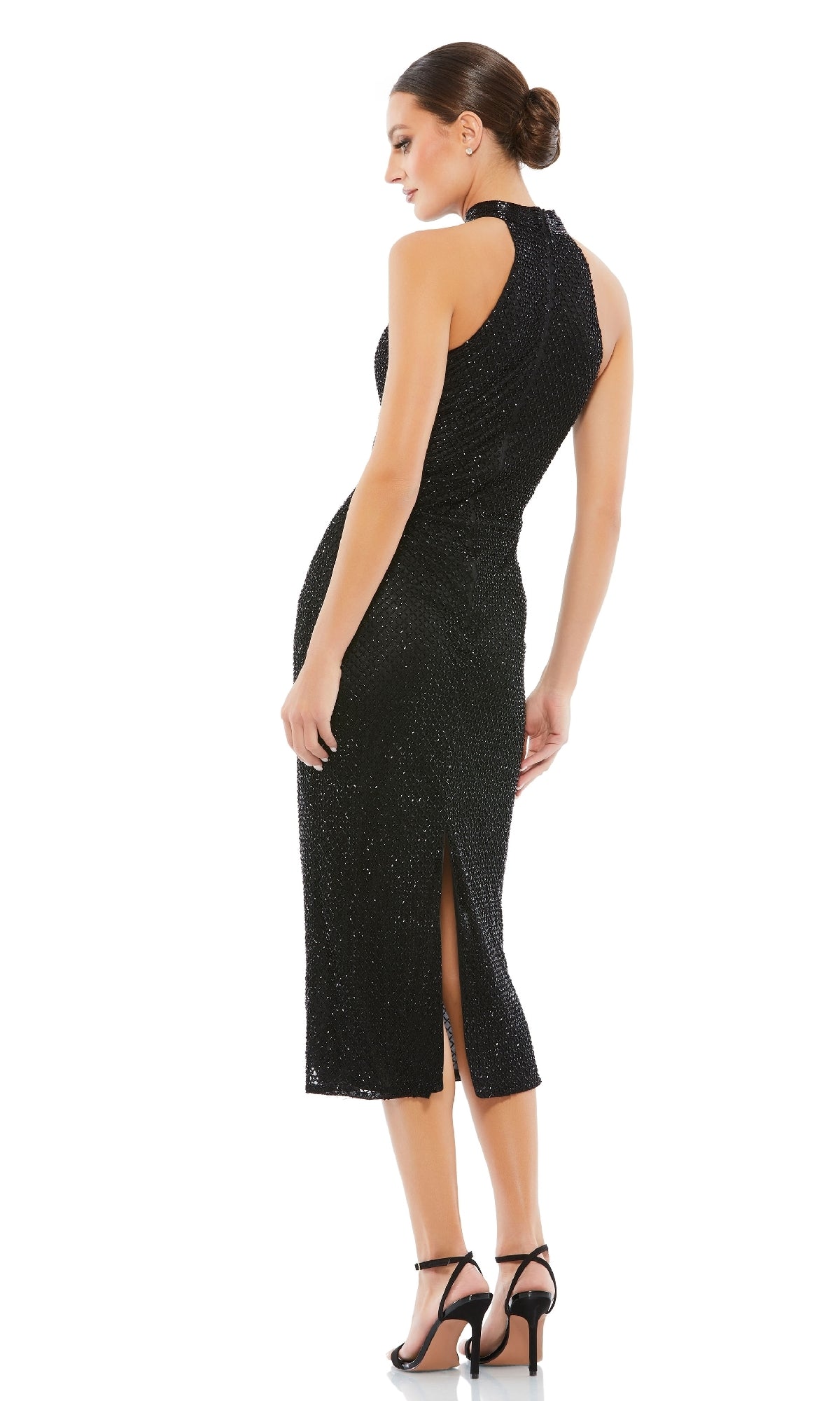A woman stands facing away, wearing the Mac Duggal 5531 high-neck black midi party dress with a back slit and black high-heeled sandals.